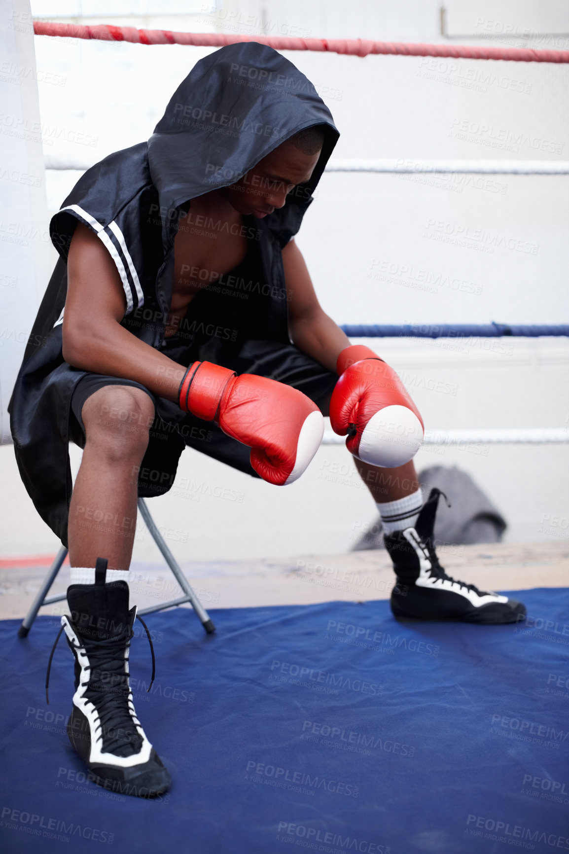 Buy stock photo African American male boxer in black hooded robe looking down