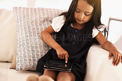 Buy stock photo Kid, little girl and tablet on sofa for entertainment, movie or online streaming at home. Young female person or child browsing, scrolling or reading ebook with technology in living room at house