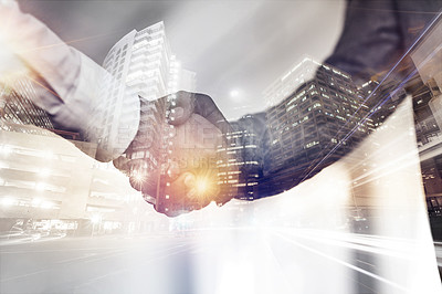 Buy stock photo Cropped shot of two unrecognizable businessmen shaking hands superimposed over a cityscape