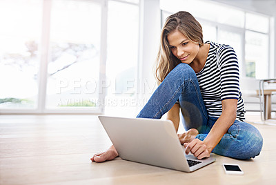 Buy stock photo Shot of a young woman sitting on the floor with her cellphone and laptop