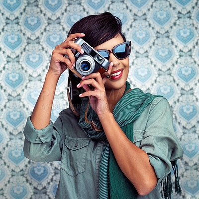 Buy stock photo Shot of a young woman posing with a camera over a patterned background
