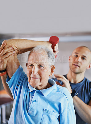 Buy stock photo Shot of a senior man working out with the help of a trainer