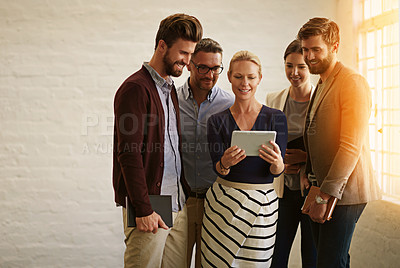 Buy stock photo Cropped shot of a business team looking at a tablet while standing in their office