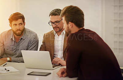 Buy stock photo Cropped shot of three businessmen looking at a laptop in the boardroom