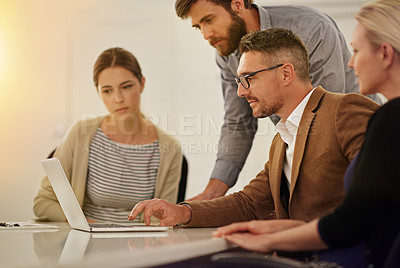 Buy stock photo Cropped shot of four businesspeople looking at a laptop in the boardroom
