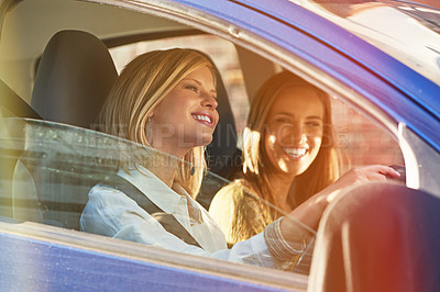 Buy stock photo Shot of two young women traveling in a car in the city
