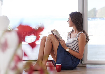 Buy stock photo Cropped shot of a young woman reading a book at home
