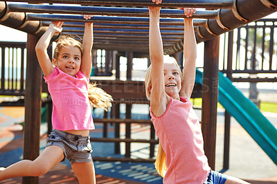 Buy stock photo Shot of two little girls hanging on the monkey bars at the playground