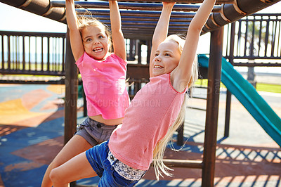 Buy stock photo Shot of two little girls hanging on the monkey bars at the playground