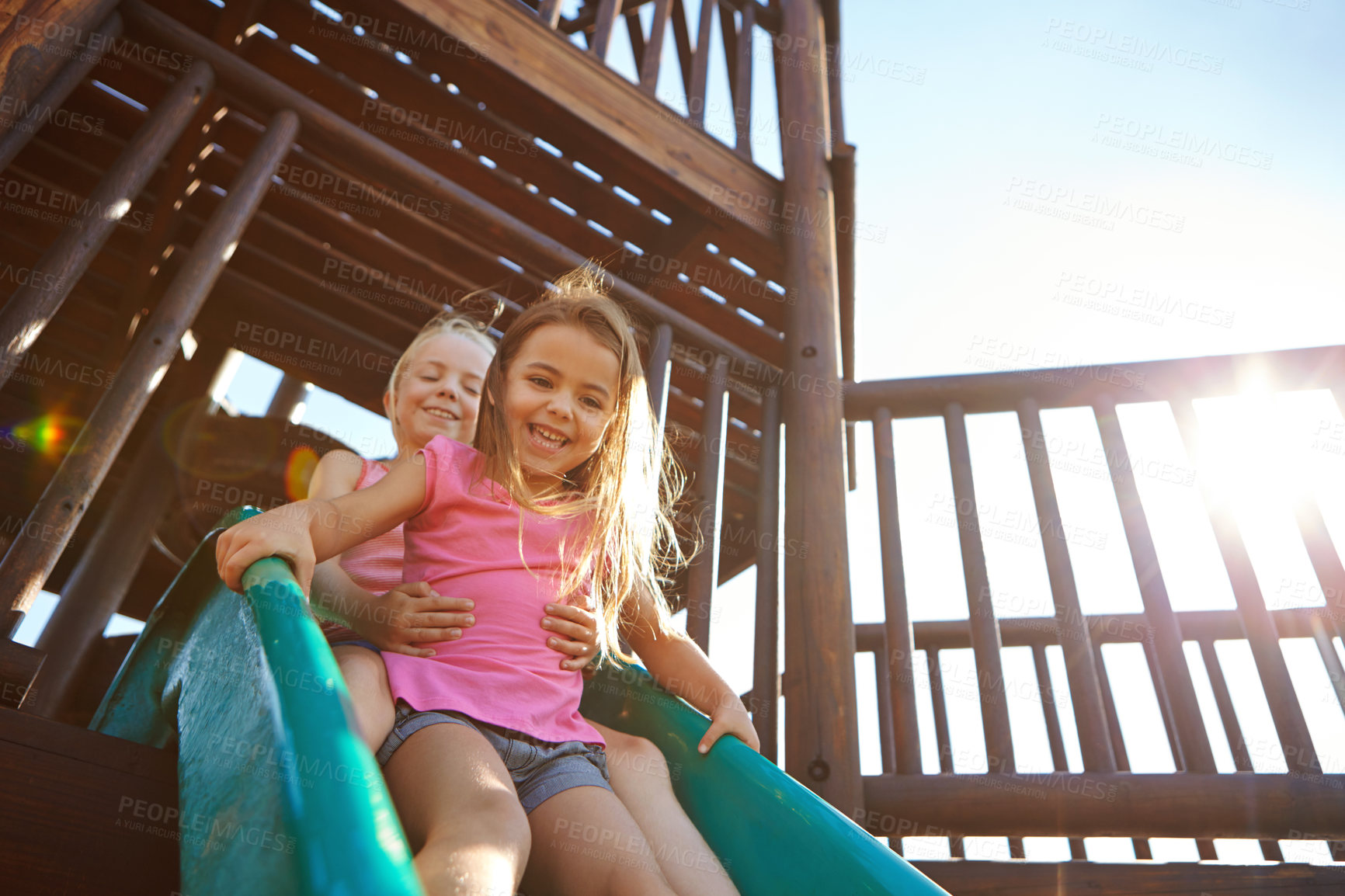 Buy stock photo Shot of two little girls on a slide at the play park