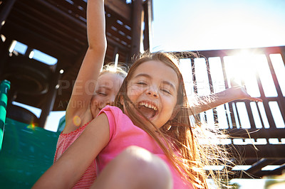 Buy stock photo Shot of two little girls on a slide at the play park