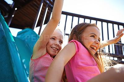 Buy stock photo Shot of two little girls on a slide at the play park