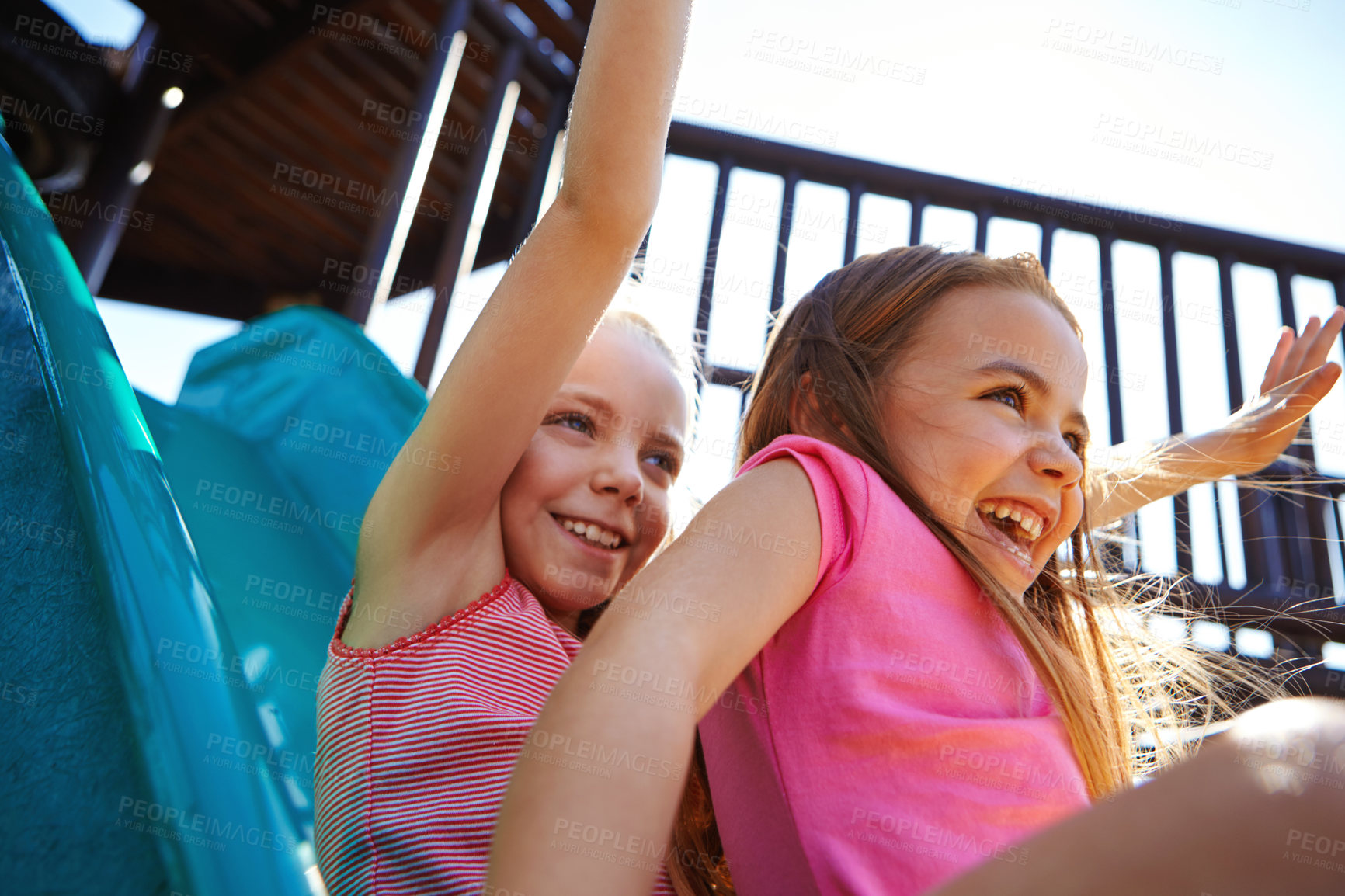 Buy stock photo Shot of two little girls on a slide at the play park