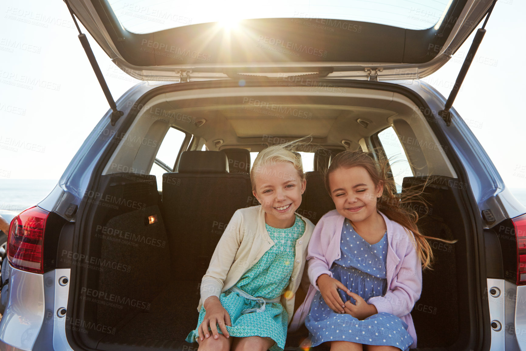 Buy stock photo Shot of two little girls sitting in the trunk of a car