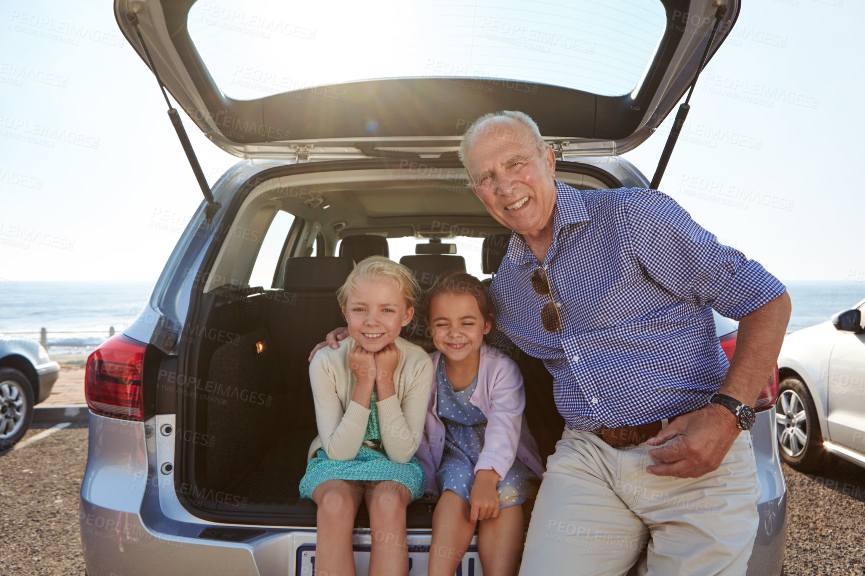 Buy stock photo Shot of two little girls sitting in the trunk of a car with their granddad