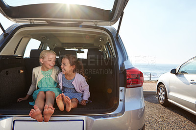 Buy stock photo Shot of two little girls sitting in the trunk of a car