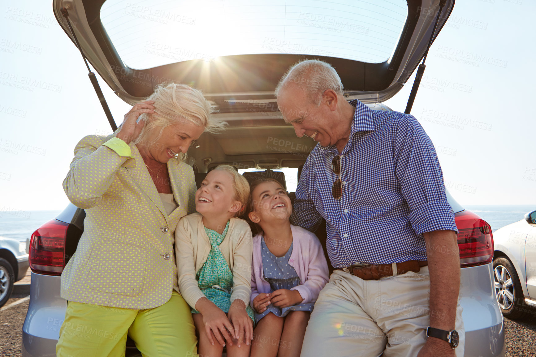 Buy stock photo Travel, grandparents or grandchildren in car trunk at beach, excitement and bonding together on road trip. Tourism, flare or family in vehicle at ocean, journey or connection in driving adventure.