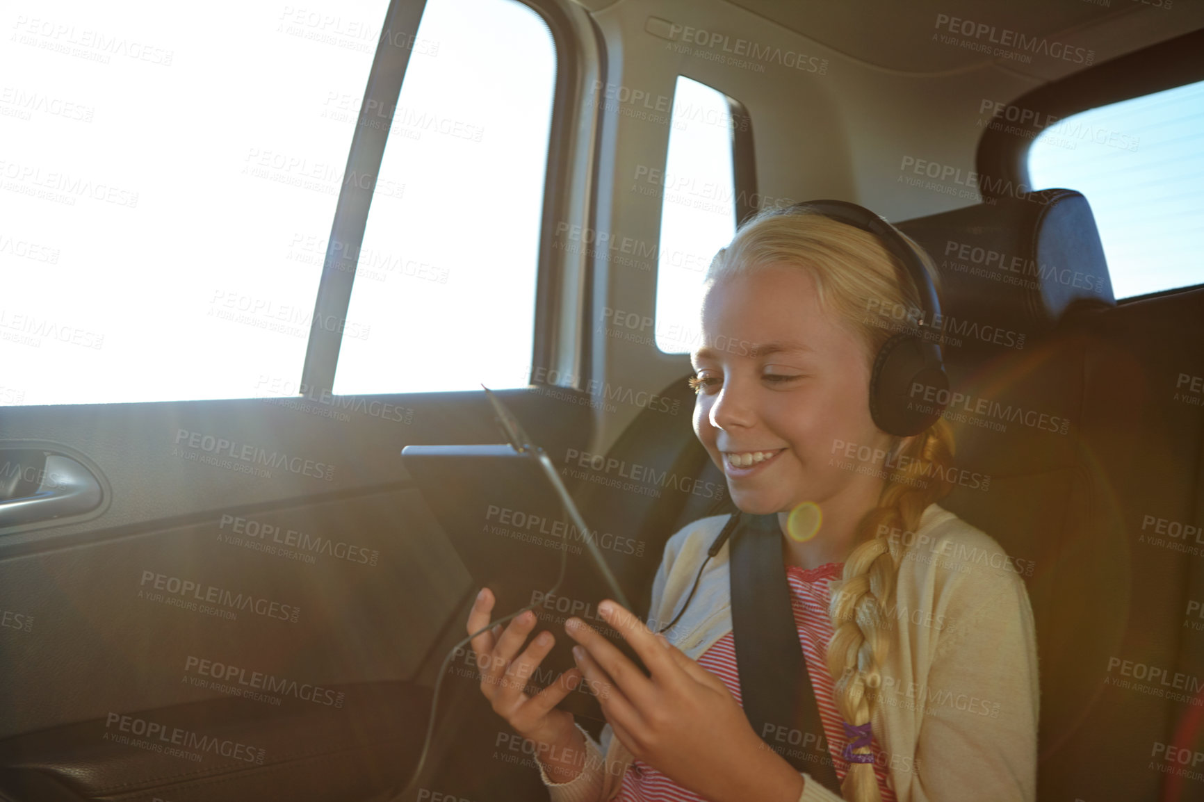 Buy stock photo Headphones, tablet and girl in car with road trip, adventure or journey for vacation. Tech, streaming and child with audio in vehicle for holiday, transport or travel with flare for entertainment