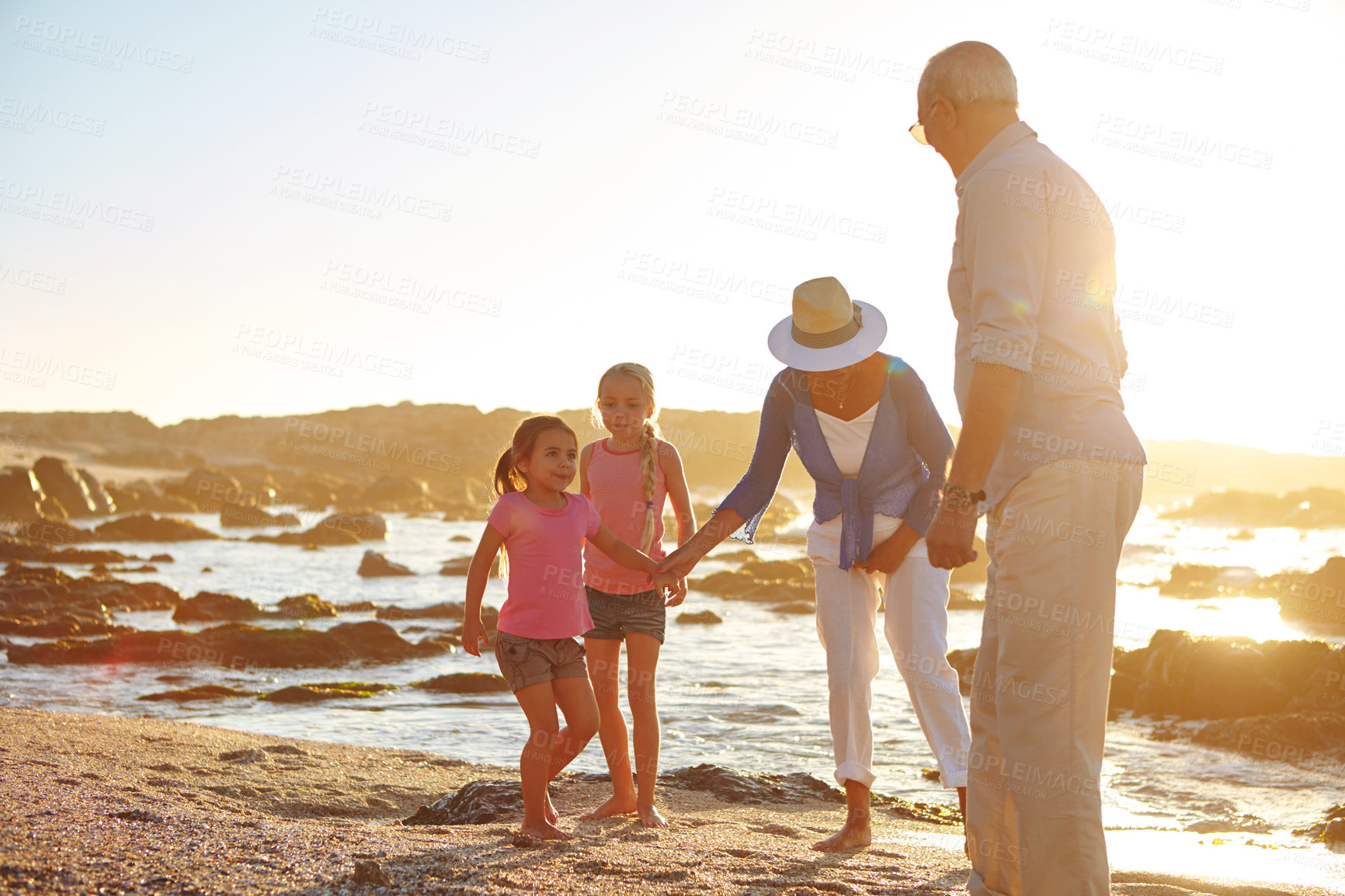 Buy stock photo Shot of a grandparents enjoying a day at the beach with their granddaughters