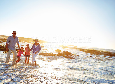 Buy stock photo Shot of a grandparents enjoying a day at the beach with their granddaughters