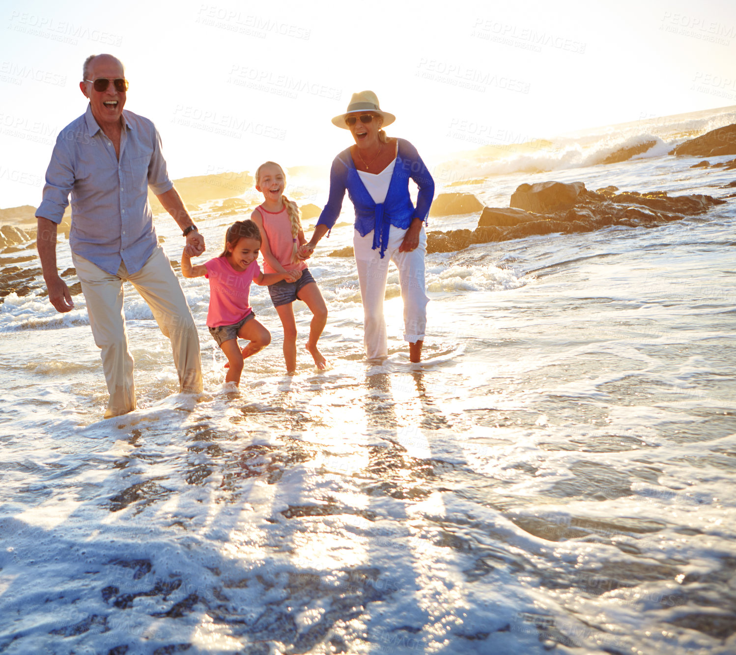 Buy stock photo Shot of a grandparents enjoying a day at the beach with their granddaughters