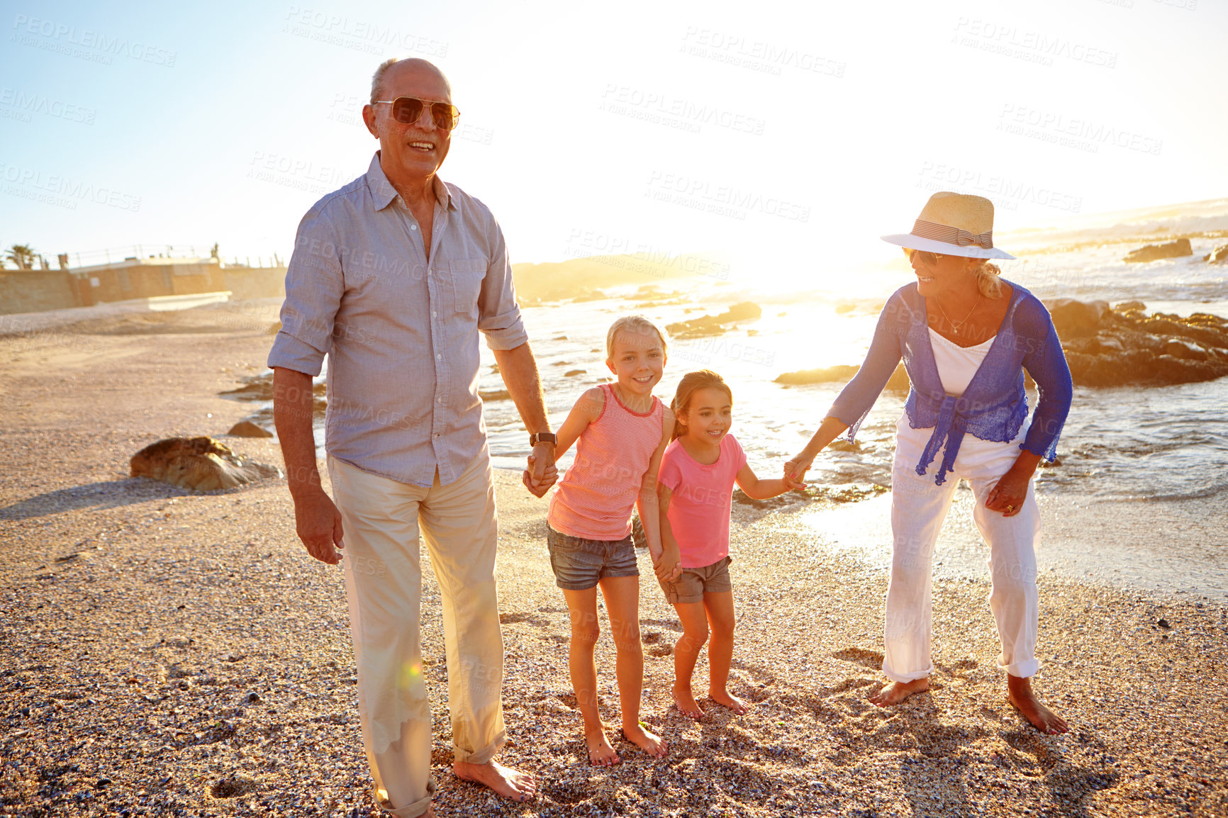 Buy stock photo Shot of a grandparents enjoying a day at the beach with their granddaughters
