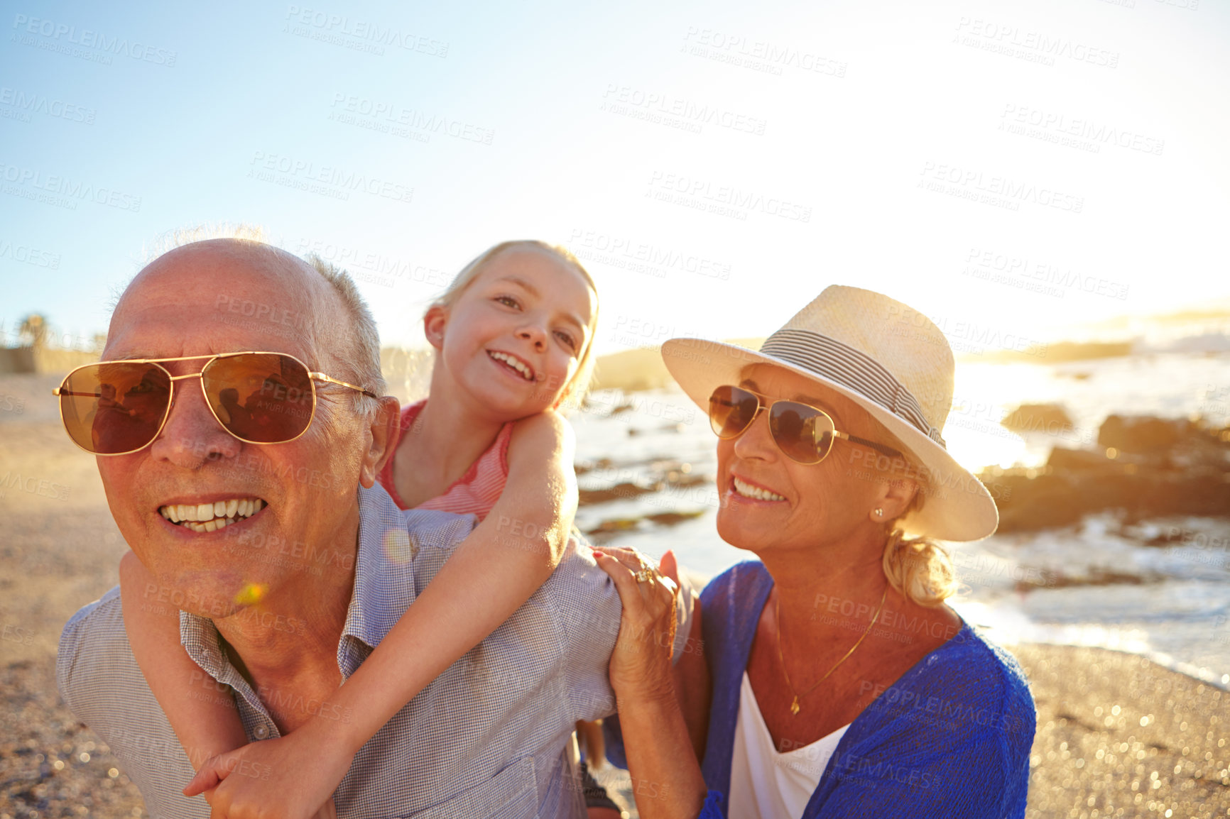 Buy stock photo Shot of a grandparents enjoying a day at the beach with their granddaughter