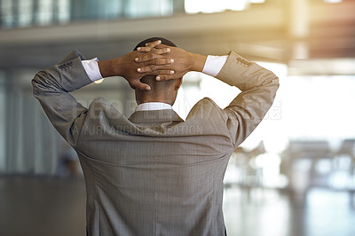 Buy stock photo Rearview shot of a businessman standing with his hands behind his head