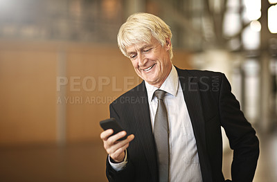 Buy stock photo Cropped shot of a senior businessman using his cellphone in the office
