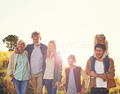 Buy stock photo A multi-generational family standing on a grassy hill together at sunset