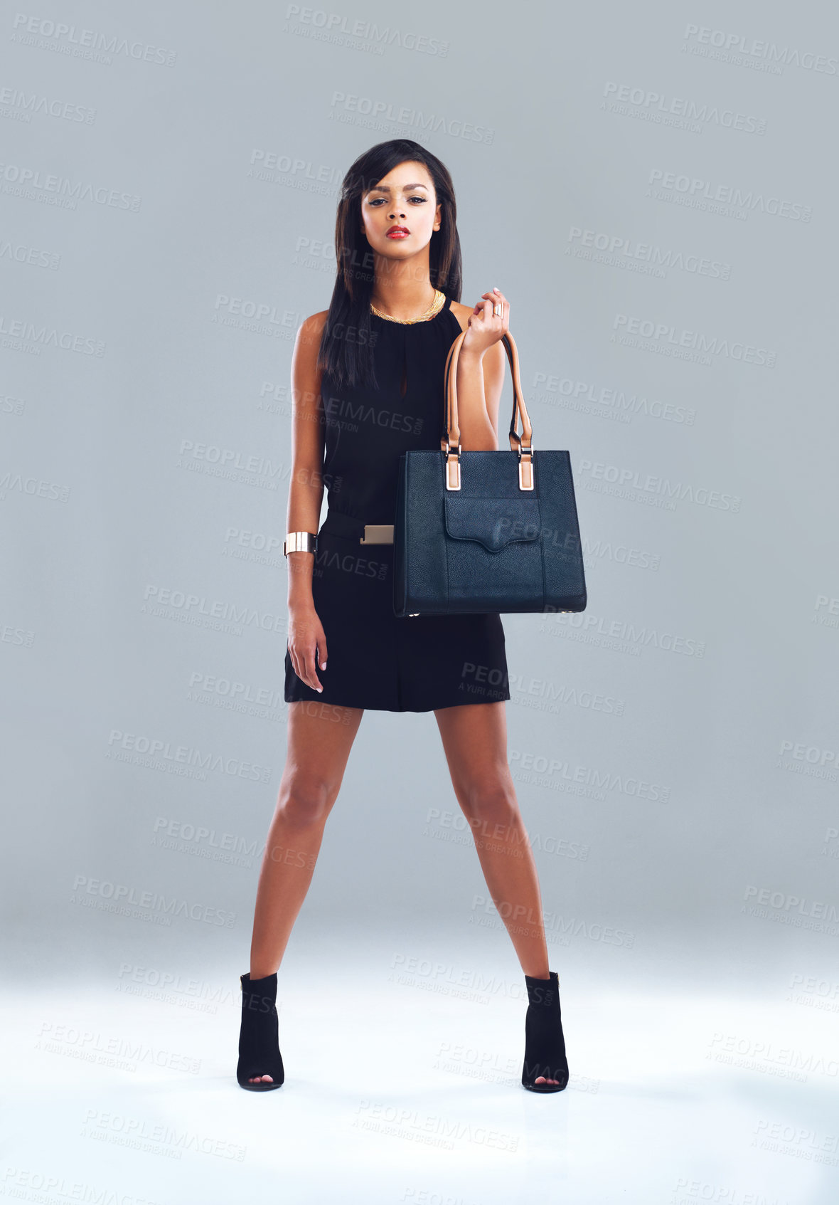 Buy stock photo Full length shot of a fashionable young woman holding her handbag
