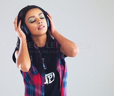 Buy stock photo Studio shot of a young woman listening to music through her headphones