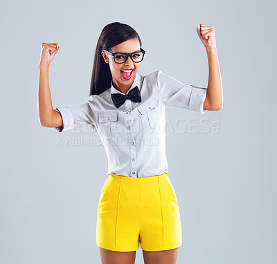 Buy stock photo Cropped portrait of a trendy young woman standing with her arms raised in celebration against a gray background