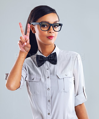 Buy stock photo Cropped portrait of a trendy young woman showing a peace sign against a gray background
