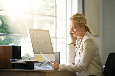 Buy stock photo Shot of a businesswoman talking on her cellphone while looking at paperwork