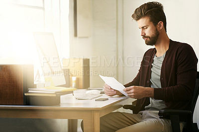 Buy stock photo Cropped shot of a businessman looking at some paperwork in his office