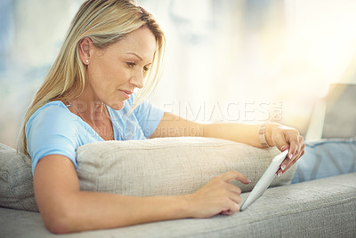 Buy stock photo Shot of a mature woman relaxing on the sofa with a digital tablet