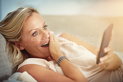 Buy stock photo Shot of a mature woman looking surprised while reading a text message at home