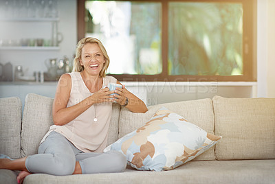 Buy stock photo Portrait of a mature woman enjoying a warm beverage while relaxing on the sofa at home