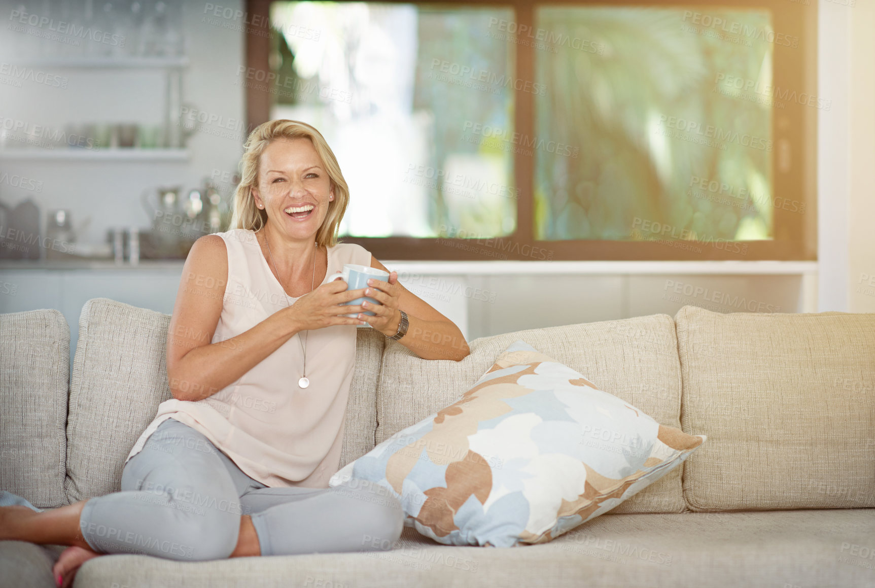 Buy stock photo Mature, woman and portrait with laughing on sofa for relax, wellness and weekend with tea break in home. Happy person, and drinking coffee on couch in living room with pride, mockup space or beverage