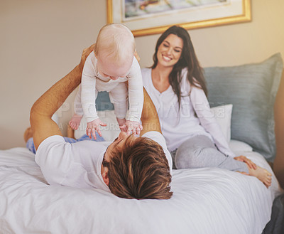 Buy stock photo Happy family, parents and playful baby in bedroom for love, care and quality time to relax together at home. Mother, father and holding infant kid for happiness, support or playing with newborn child