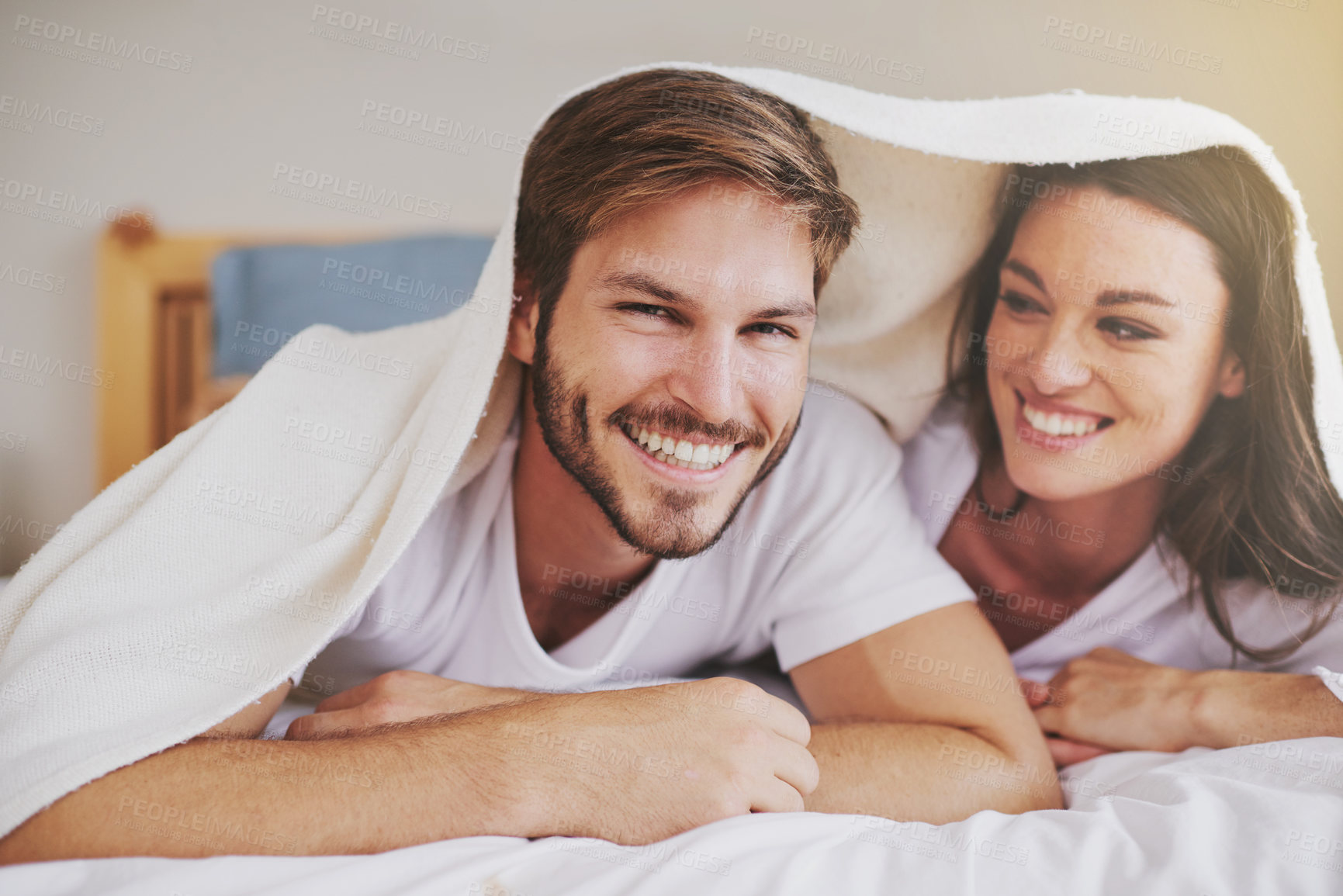 Buy stock photo Smile, love and couple with blanket for relaxing, bonding and resting on bed together at home. Happy, romantic and young man and woman laying with duvet in bedroom at hotel, house or apartment.