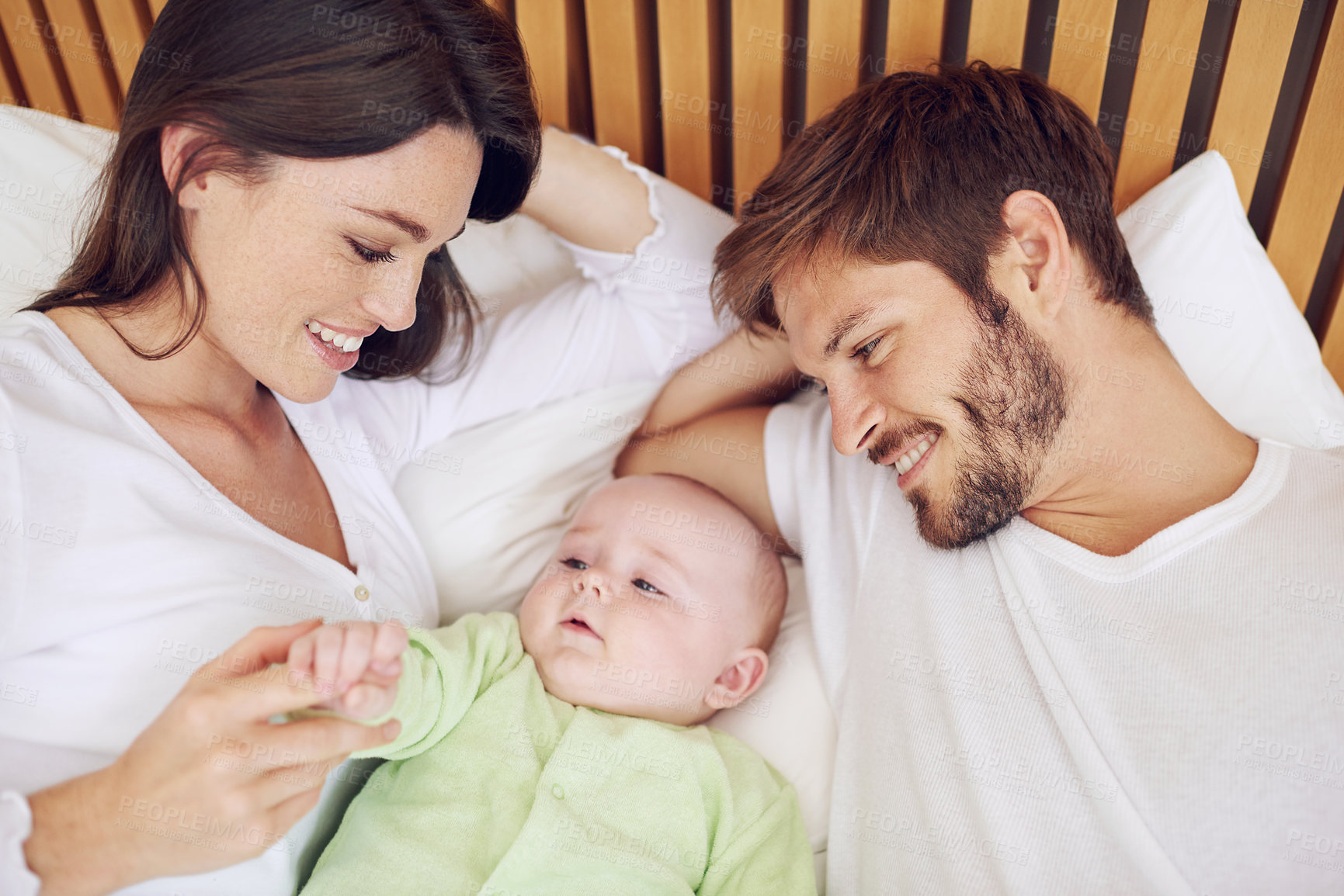 Buy stock photo Top view, parents and smile of baby in bedroom for love, care and quality time together at home. Happy mother, father and family relax with cute newborn kid on bed for support, development and joy