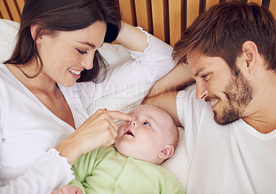 Buy stock photo Top view, happy parents and playful baby in bedroom for love, care and quality time together at home. Family, father and mother touch nose of cute newborn kid on bed with smile, fun and relaxing bond