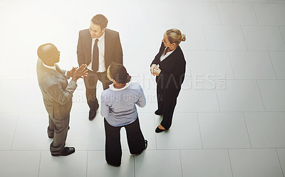 Buy stock photo High angle shot of a group of businesspeople talking in the office lobby