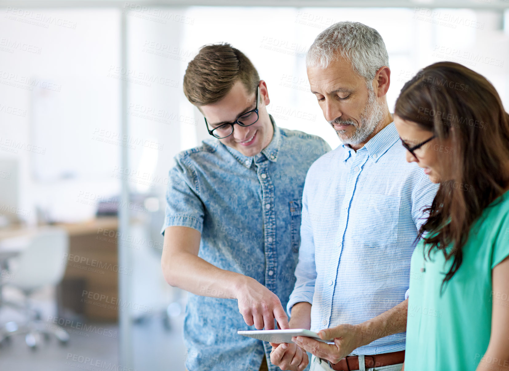 Buy stock photo Cropped shot of a group of creative businesspeople looking at a tablet