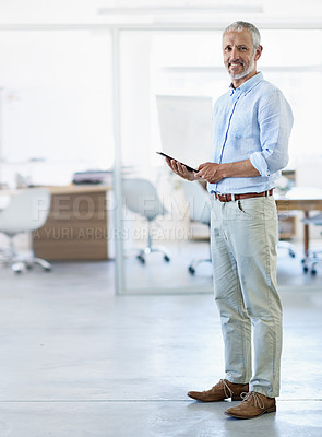 Buy stock photo Full length portrait of a mature businessman using a tablet in his office