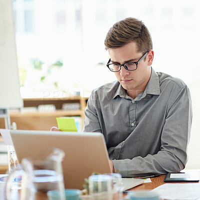 Buy stock photo Shot of a male designer working on a laptop in an office