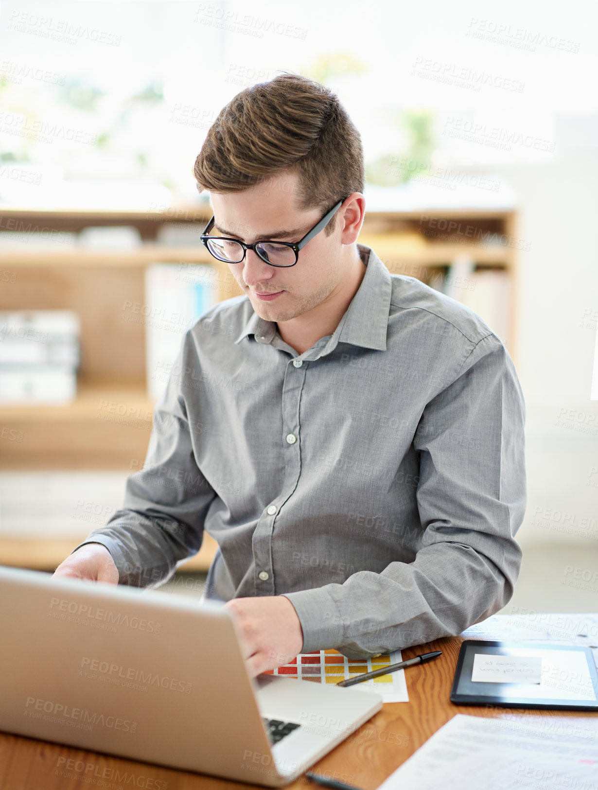 Buy stock photo Shot of a male designer working on a laptop in an office