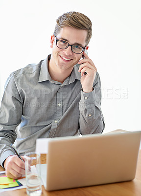Buy stock photo Shot of a male designer talking on his cellphone while working at his laptop